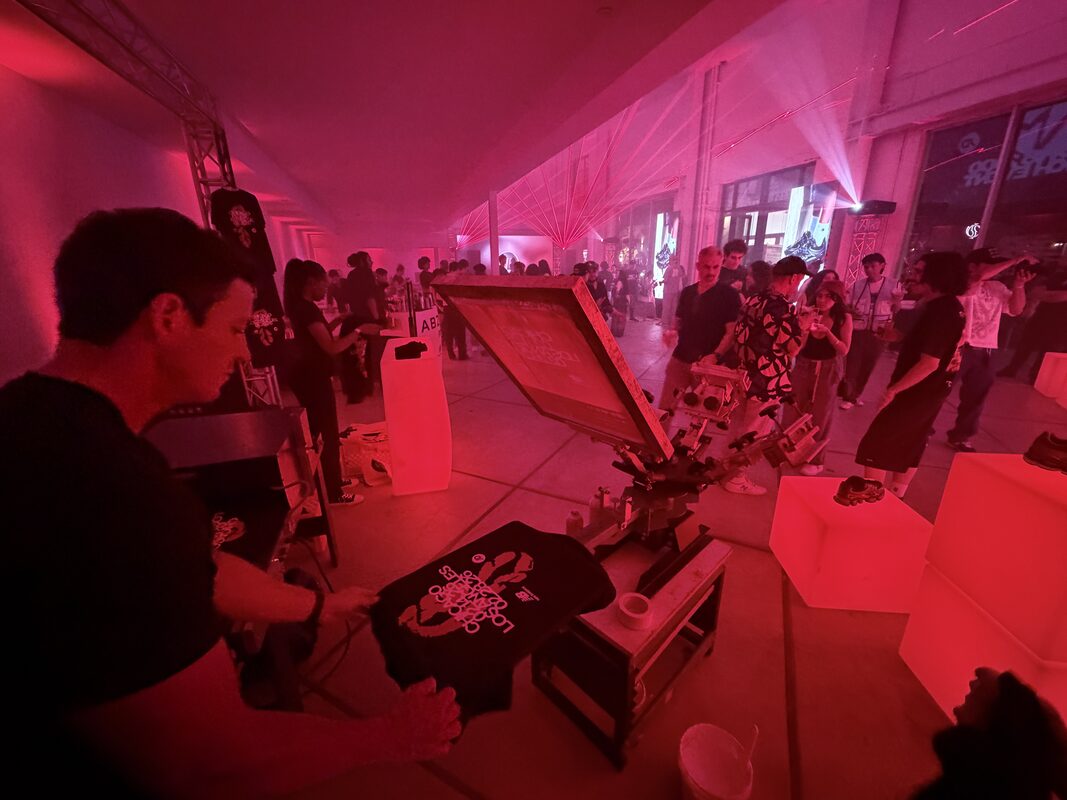 Merch Troop operator heat-pressing a full-color DTF transfer onto a shirt at a live event station