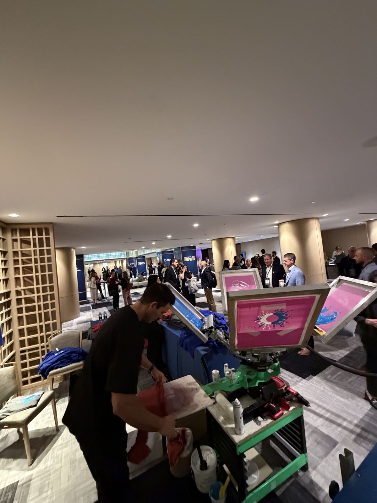Live printing demonstration at an event with multiple framed sample prints displayed and a crowd of attendees viewing the equipment
